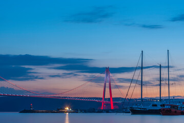 istanbul yavuz sultan selim bridge taken from the beach towards sunset people dogs with blue sea and sky and evening lighting