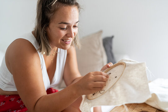 Woman embroidering on fabric frame.