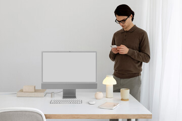 A young man in a office near a computer. White computer screen, mockup