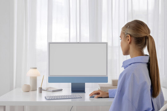 a woman works at a computer with a white screen in a modern office