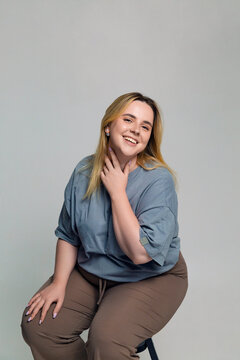 Happy young plus size woman sitting on stool in room 