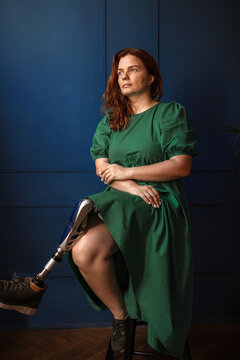 A thoughtful woman with a prosthetic leg is sitting in the studio