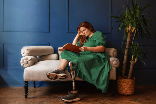 a disabled woman with a prosthetic leg enthusiastically reads a book