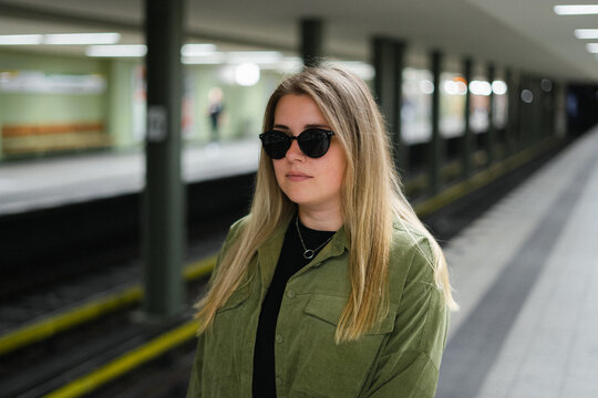 Young woman in sunglasses waiting for train at underground station