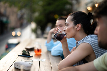 Young woman having drink/cocktail at outdoor bar with friends