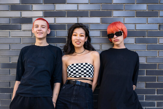 Stylish diverse young friends standing near  wall