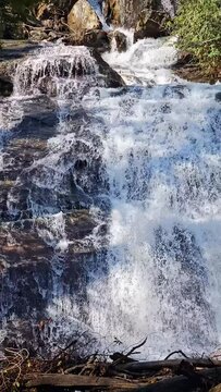tilt footage of the rushing waters of Smith Creek and waterfall at Anna Ruby Falls with rocks and lush green trees and plants in Helen Georgia USA