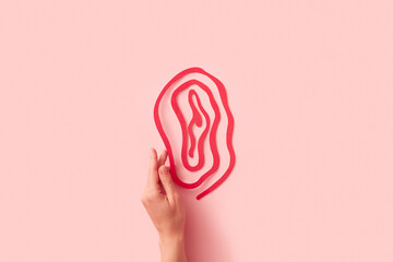 Close up of female hand touching red papercraft woman's vulva