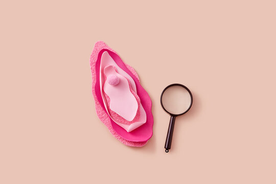 Magnifying glass lying near female vulva made of decorative materials