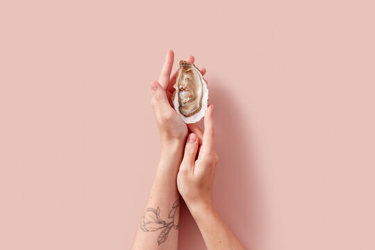 Female hands holding fresh opened oyster with pearl inside