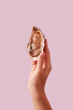 Crop of woman's hand holding fresh raw oyster in open shell