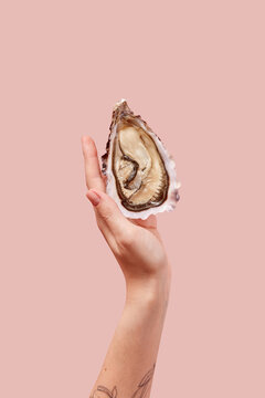 Crop of female hand holding fresh opened oyster