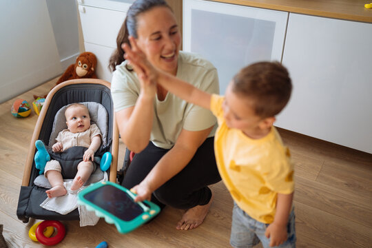 Mother and son near baby in rocker with high fives