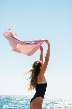 Woman holding towel above her head on the beach