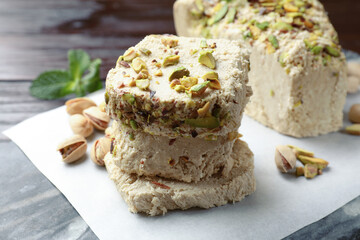 Pieces of tasty halva with pistachios on table, closeup