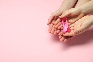 Breast cancer awareness. Women holding pink ribbon on color background, top view. Space for text