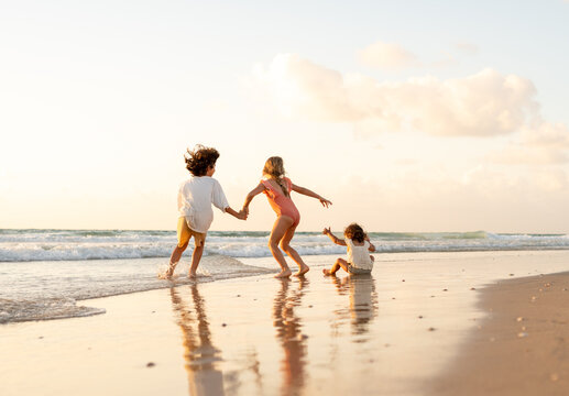 Siblings running on an empty beach.