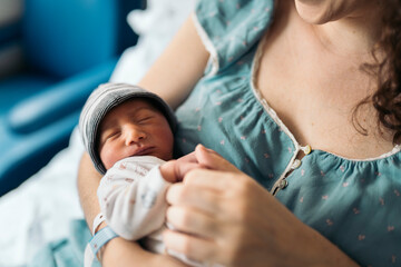 Mother holding a Newborn baby In Hospital room
