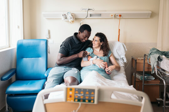 Multicultural couple caring the newborn baby in the hospital room