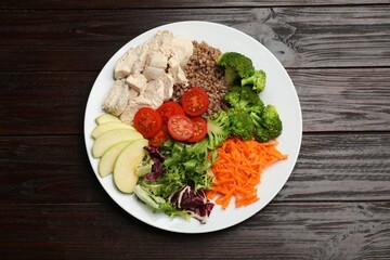 Balanced diet and healthy foods. Plate with different delicious products isolated on wooden table, top view