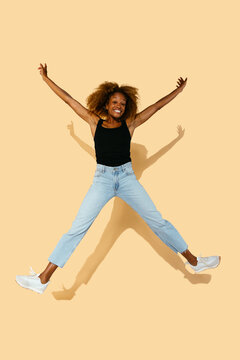 Excited curly woman jumping in studio