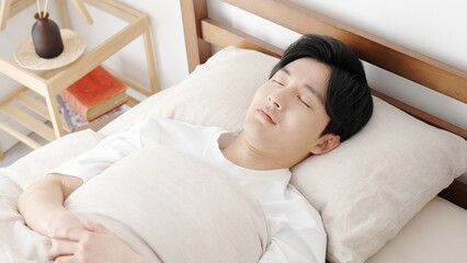 明るい部屋で寝るアジア人男性
