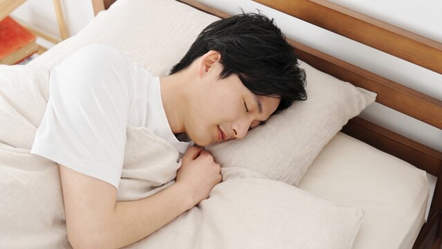 寝返りを打つアジア人男性