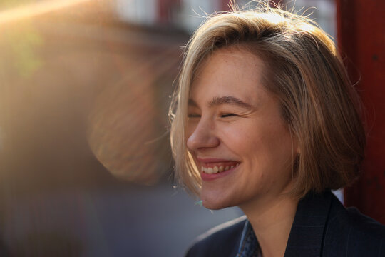 Happy woman with short hair smiling with sunlight effect on sunny day
