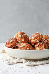 Stack of Chouquettes served in a white bowl on a linen tablecloth shot portrait style