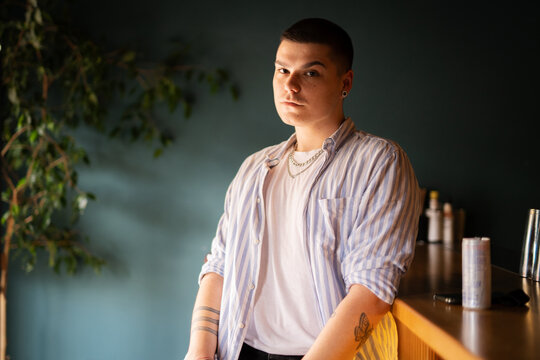 Young adult man sitting at a bar looking at camera. Portrait 