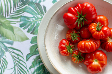 A bowl of homegrown beefsteak tomatoes on a palm patterned background.
