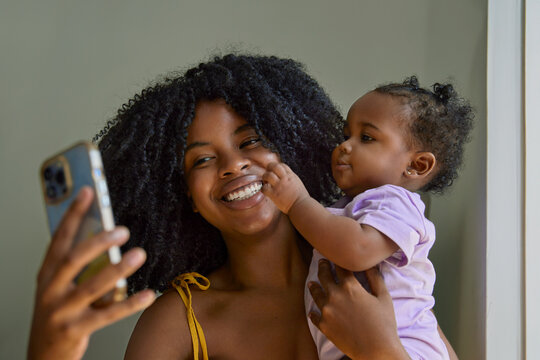 A woman is holding her baby and engaging in a video call.