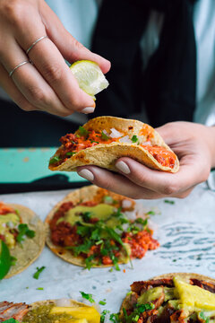 Woman holding taco and squeezing line on it, tacos close up
