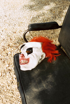 clown mask on an outdoors bench, 35mm