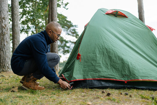 A man sets up a tent in the forest
