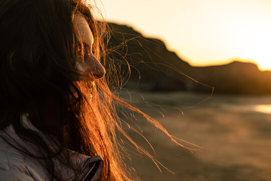 profile of woman with long hair blowing with the wind at sunset