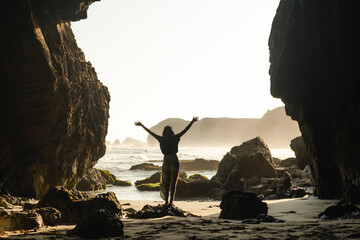 Travel woman With raised arms on a rocky beach