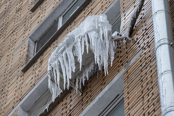 Icicles hang from an air conditioning unit on a brick building. Frozen Air Conditioning Unit with Icicles