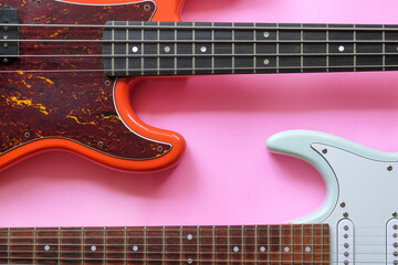 Electric guitar and bass guitar on a pink background with copy space.