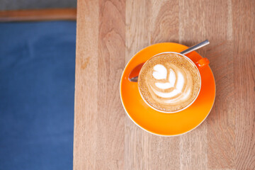 top view of orange color coffee cup on wooden plate.