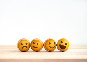 Customer service evaluation, marketing feedback, ratings, satisfaction survey, mental health and psychology concept. Four Wooden balls with cute emoticon various emotions face on white background.
