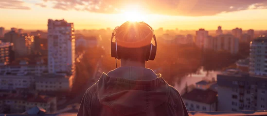 Poster a man listening music use headphones with cityscape view © Menganga