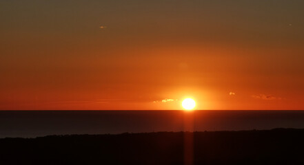 Il Sole accecante che all’alba sorge dal mare visto da sopra le colline 
