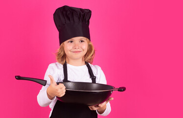 Kid chef cook cookery with pan. Excited chef cook. Child wearing cooker uniform and chef hat preparing food, studio portrait.