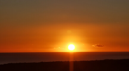 Il Sole accecante che all’alba sorge dal mare visto da sopra le colline 