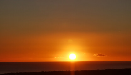 Il Sole accecante che all’alba sorge dal mare visto da sopra le colline 