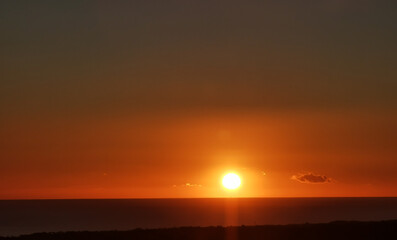 Il Sole accecante che all’alba sorge dal mare visto da sopra le colline 