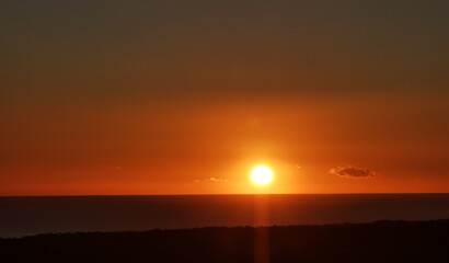 Il Sole accecante che all’alba sorge dal mare visto da sopra le colline 