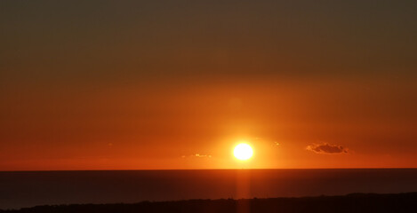 Il Sole accecante che all’alba sorge dal mare visto da sopra le colline 