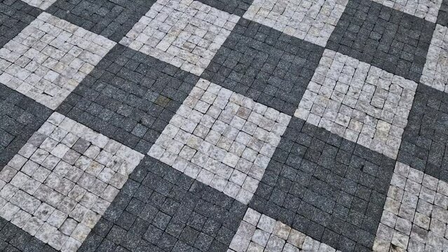 chess board made of small marble cubes. the gray and white mosaic in the square is a classic visual cliché. pavers work advertising spot. surface detail